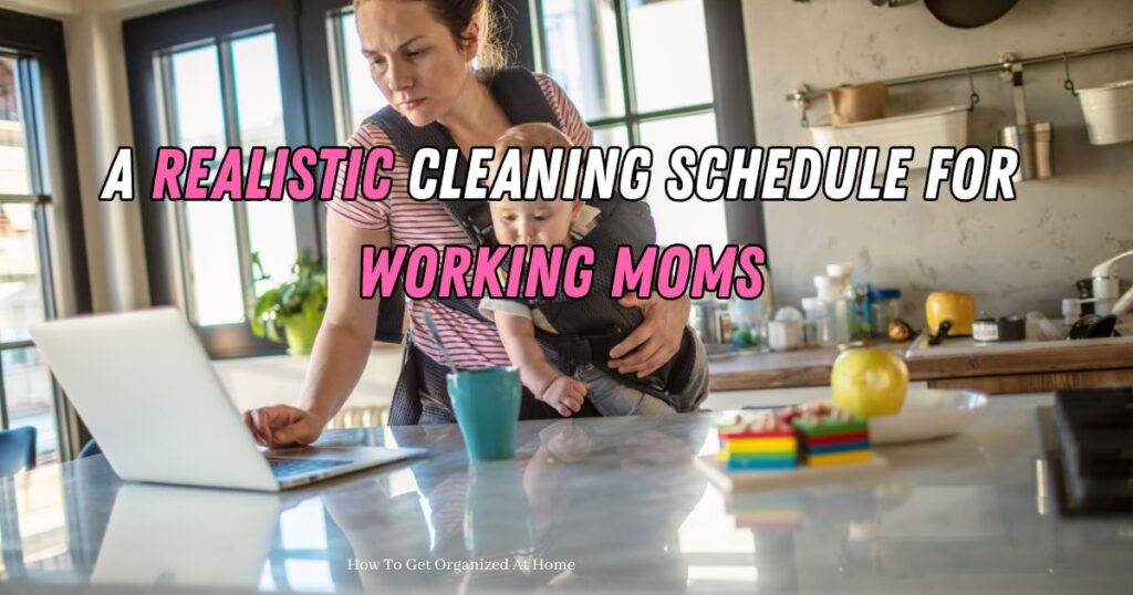 working mom using laptop with baby strapped to her front in a kitchen with toys on counter and food. Words on image say &lsquo;Creating A Realistic Cleaning Schedule For Working Moms&rsquo;
